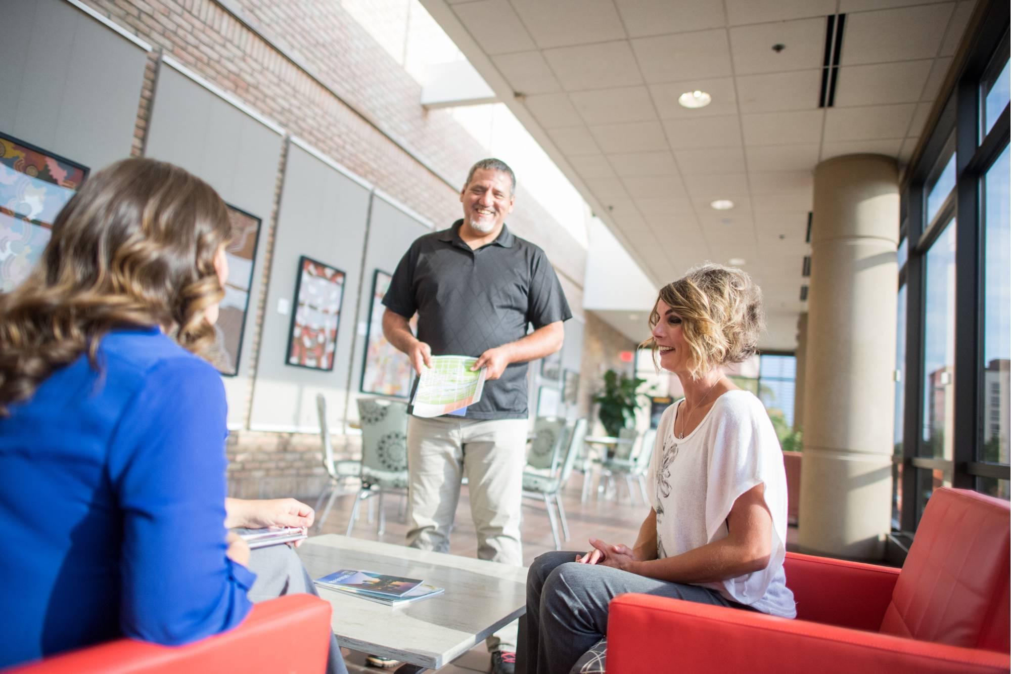 Two adult students speaking with their advisor before class.